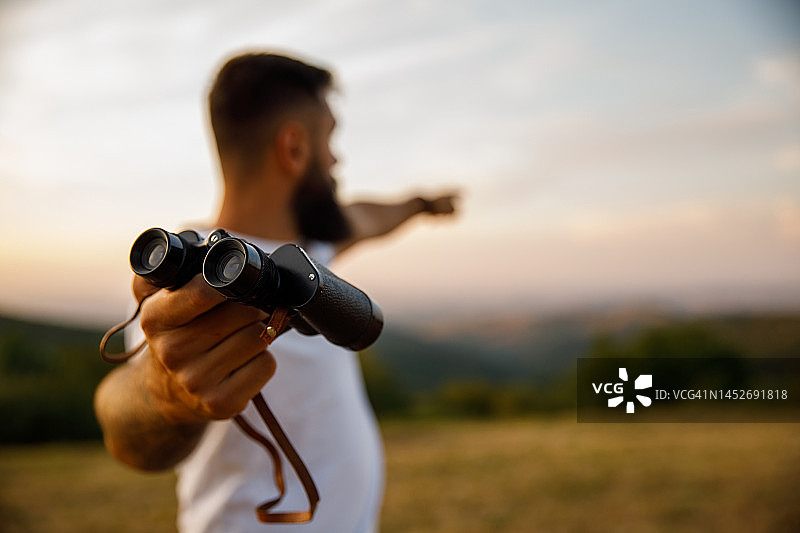 男人给你望远镜并指向远方图片素材