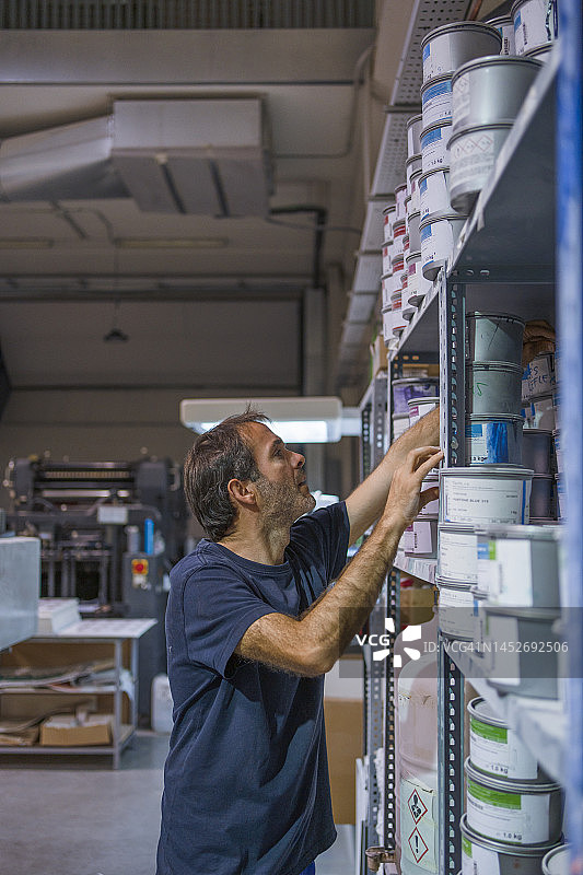寻找完美的油墨：胶印机操作员在架子上寻找理想的颜色图片素材