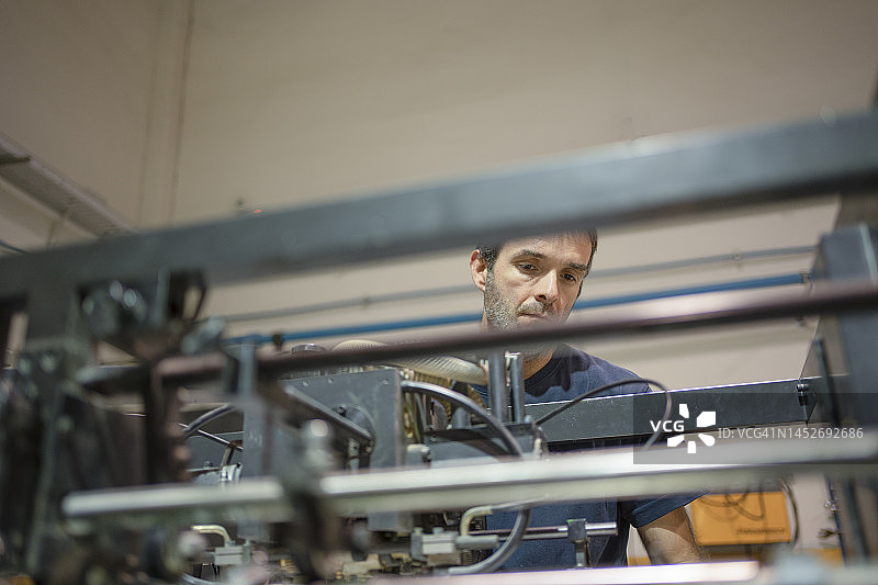 在印刷机房工作的胶印机操作员图片素材