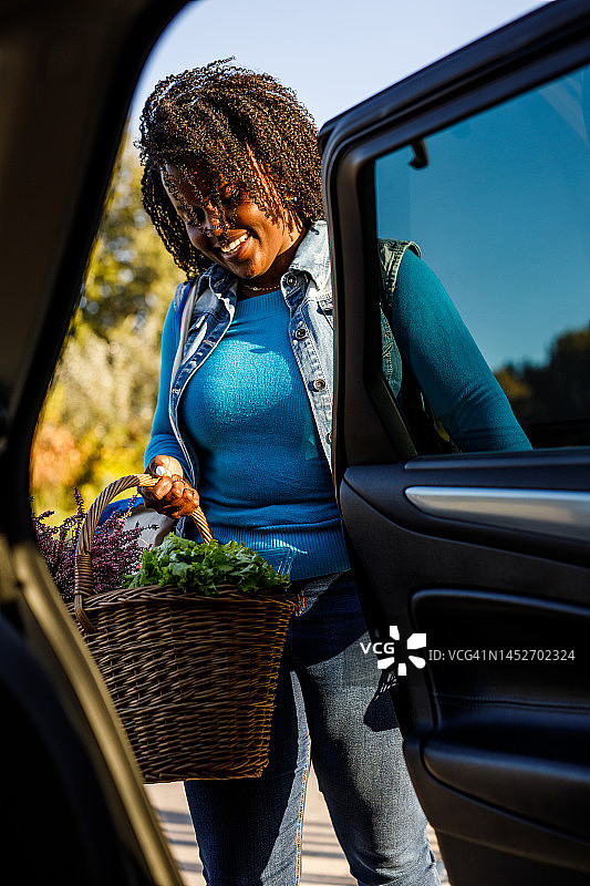 年轻女人逛完农贸市场后，把食品装进汽车后座图片素材
