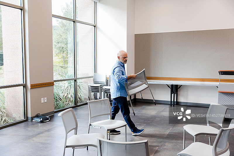 搬运椅子参加会议的中年男人图片素材