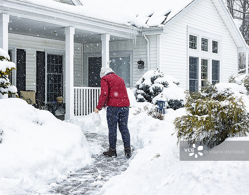 在清理过的走道上撒融冰晶体的女人图片素材