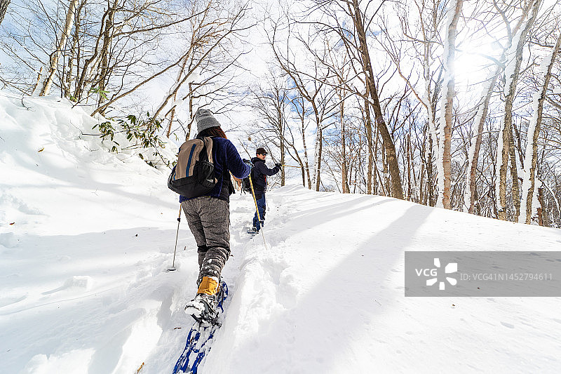 在冬季森林中穿着雪鞋徒步的两人图片素材