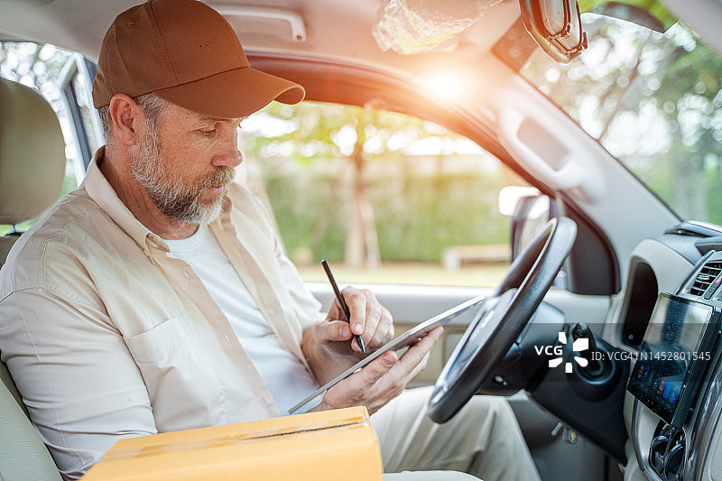 驾驶货车，前排座位放着包裹的送货员图片素材