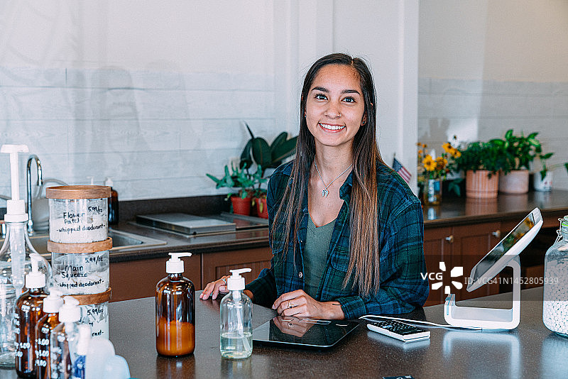 在零浪费商店收银台的快乐年轻拉美裔女子肖像图片素材