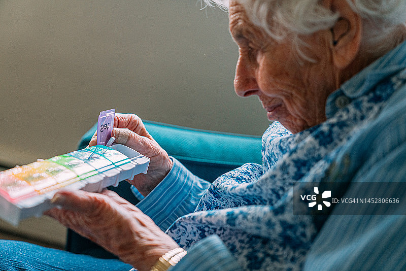 一位101岁老人拿着每周处方药和维生素补充剂整理盒图片素材