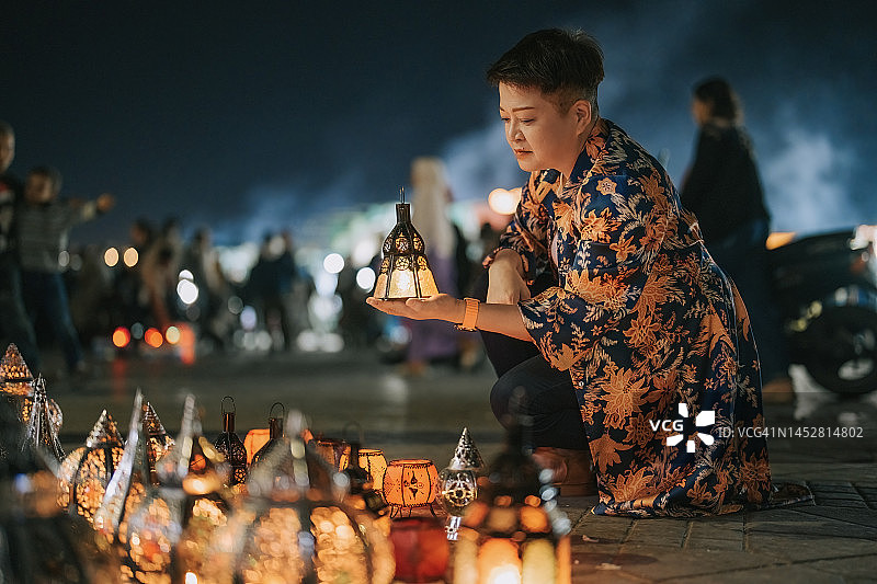 中国女性游客在摩洛哥马拉喀什德吉玛广场夜市摊位挑选灯笼图片素材