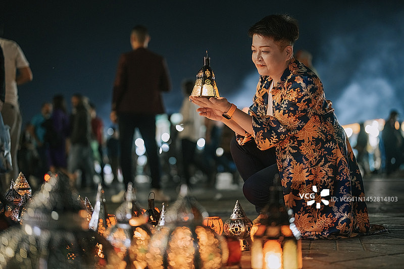 中国女性游客在摩洛哥马拉喀什德吉玛广场夜市摊位挑选灯笼图片素材