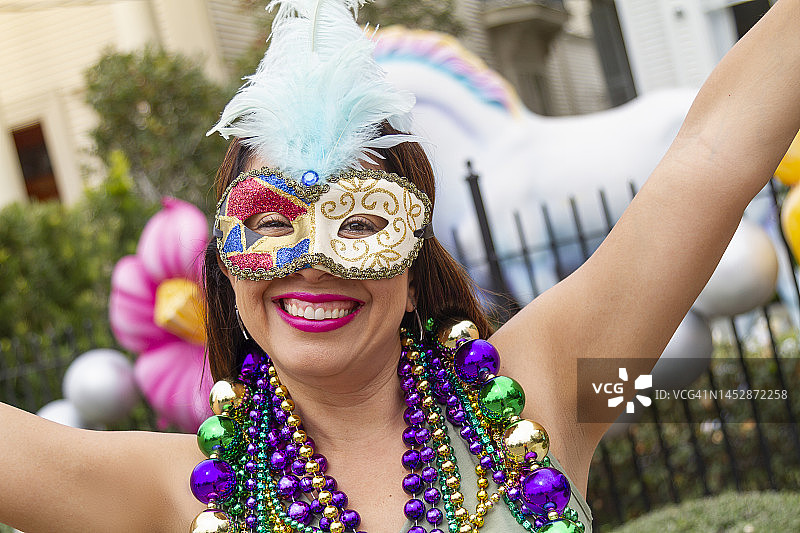 在墨西哥新奥尔良街头庆祝狂欢节的年轻拉丁裔女游客，戴着面具，穿着戏服和项链图片素材