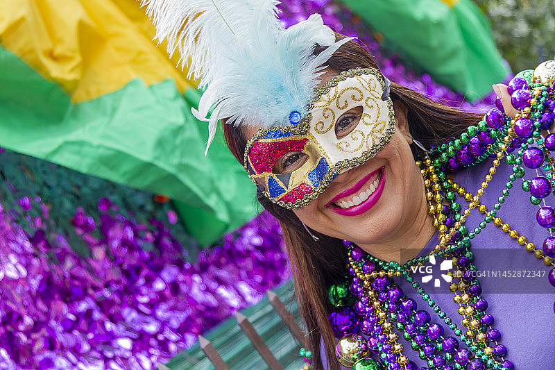 在墨西哥新奥尔良街头庆祝狂欢节的年轻拉丁裔女游客，戴着面具，穿着戏服和项链图片素材