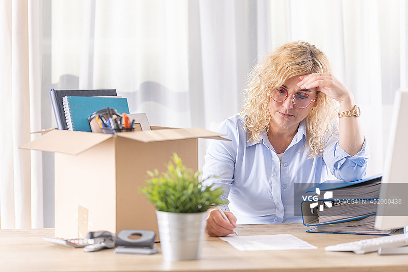 沮丧的女人在办公室签署辞职信图片素材