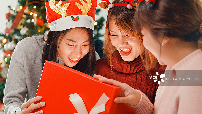 亚洲年轻朋友在客厅沙发上打开圣诞礼物图片素材