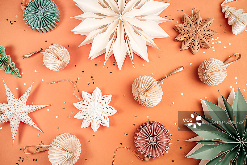 橙色背景上的纸雪花和圣诞树装饰品，节日气氛浓厚的新年快乐概念图片素材