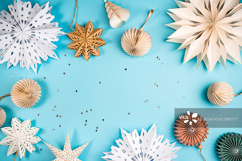 蓝色背景上节日气氛的剪纸雪花和圣诞树装饰品。圣诞快乐，新年快乐概念图案，带复制空间图片素材