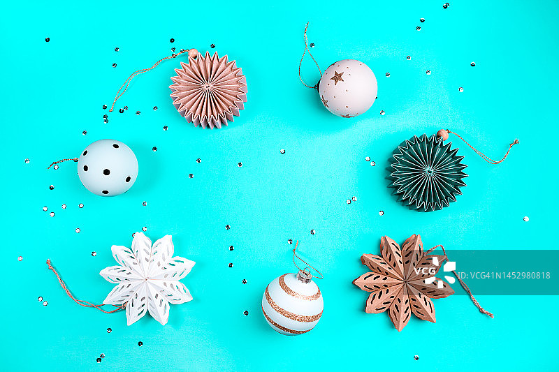蓝色背景上节日气氛的剪纸雪花和圣诞树装饰品。圣诞快乐，新年快乐概念图案，带复制空间图片素材