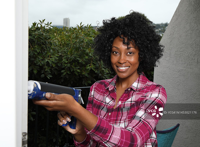 对着镜头微笑的非裔美国女性填缝枪工人图片素材