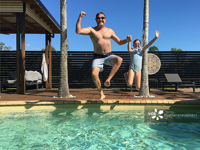 快乐的父女在暑假一起跳入游泳池图片素材