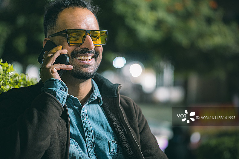 单身男人坐在公园长椅上使用智能手机图片素材