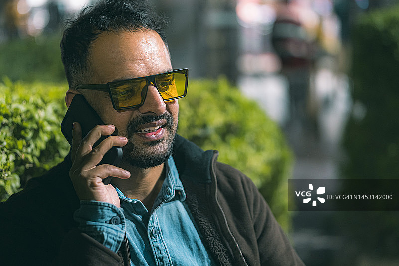 单身男人坐在公园长椅上使用智能手机图片素材