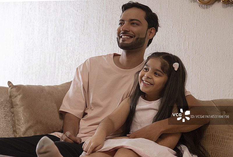 父女在家中沙发上看向远方图片素材