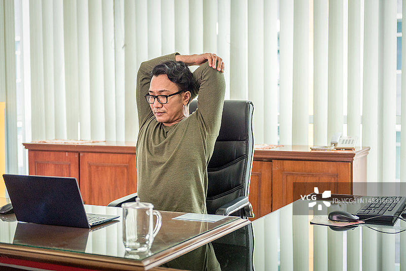 在办公室伸展肩膀的亚洲男人图片素材