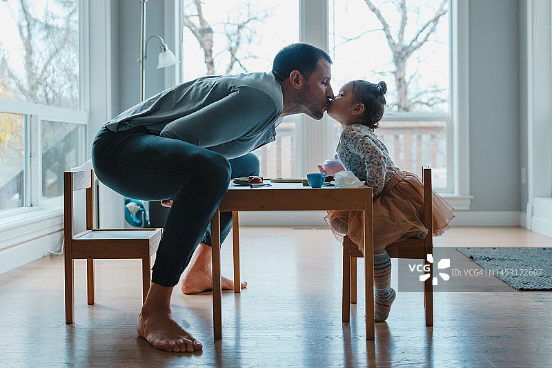 父亲亲吻蹒跚学步的女儿图片素材