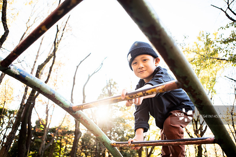男孩在公园里尝试攀爬单杠图片素材