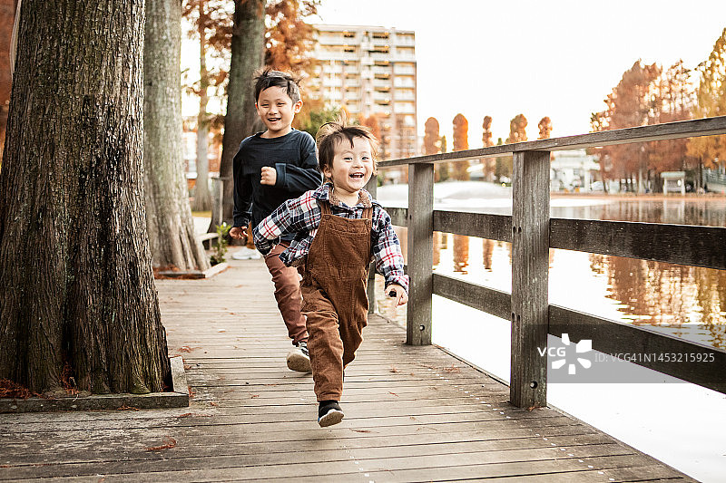 两岁和五岁的兄弟在公园里追逐玩耍图片素材