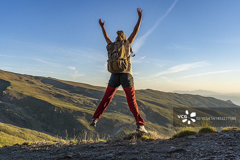 在山景中跳跃庆祝的背包女徒步者图片素材