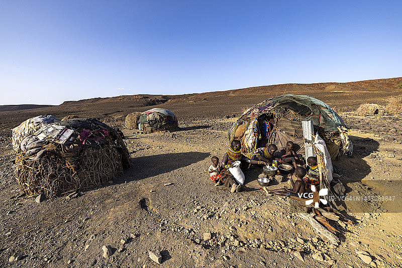 极端贫困、干旱和气候变化导致营养不良的儿童，母亲在住所前准备玉米粥和鱼，肯尼亚图片素材