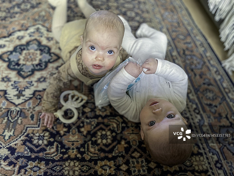 可爱的双胞胎宝宝躺在地板上图片素材