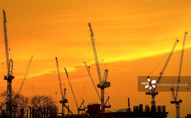 日出时分的工业建筑起重机和建筑轮廓图片素材