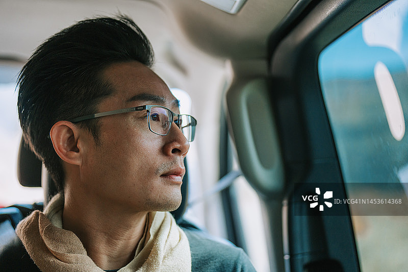 独自旅行的亚洲中国男人在摩洛哥公路旅行时看着车窗外图片素材