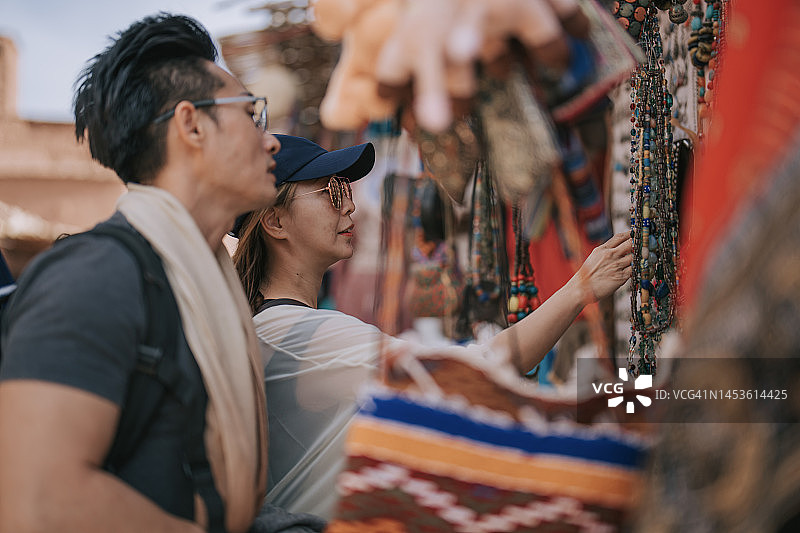 中国夫妇在摩洛哥阿伊特·本·哈杜老村的露天市场看围巾图片素材