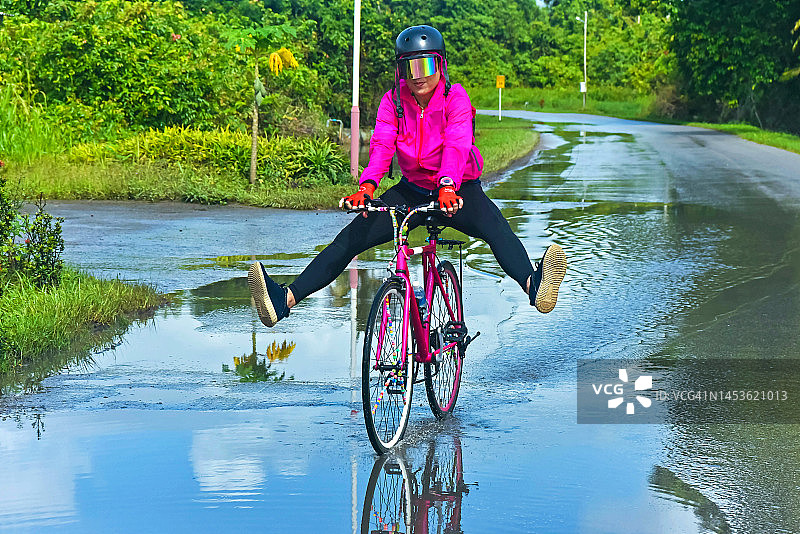 五十多岁的亚洲中年妇女在湿滑的路上骑自行车图片素材