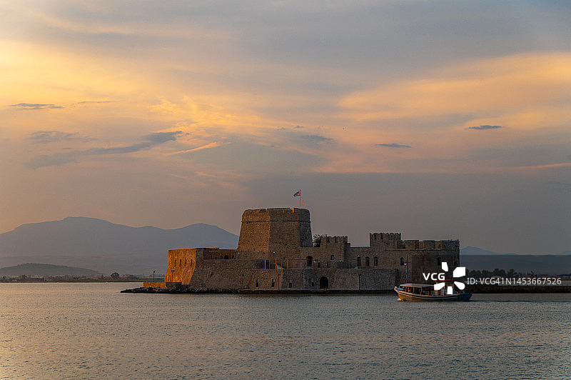 在希腊纳夫普利奥，游船在日落时接近布尔齐水上城堡图片素材