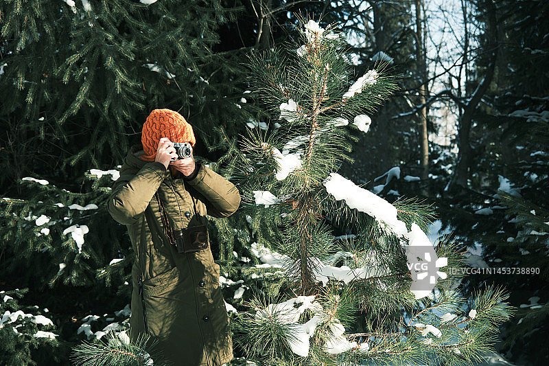 女游客在冬季公园用老式胶片相机拍照图片素材