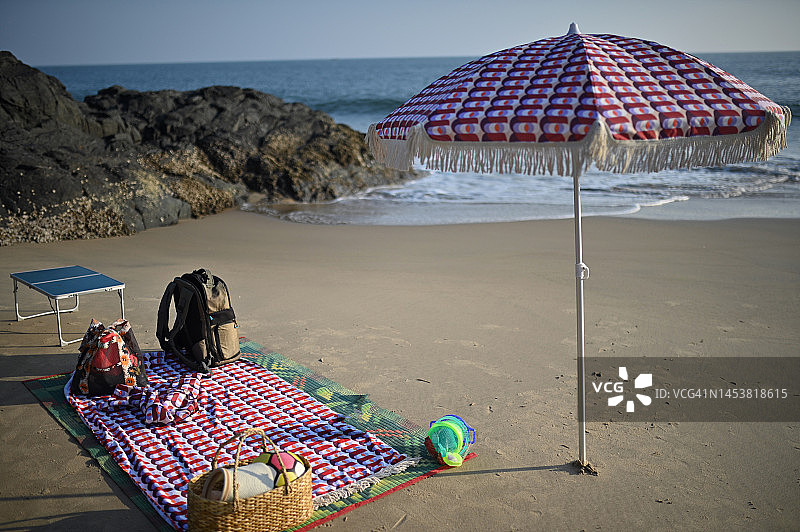 沙滩上的遮阳伞、野餐垫和篮子图片素材