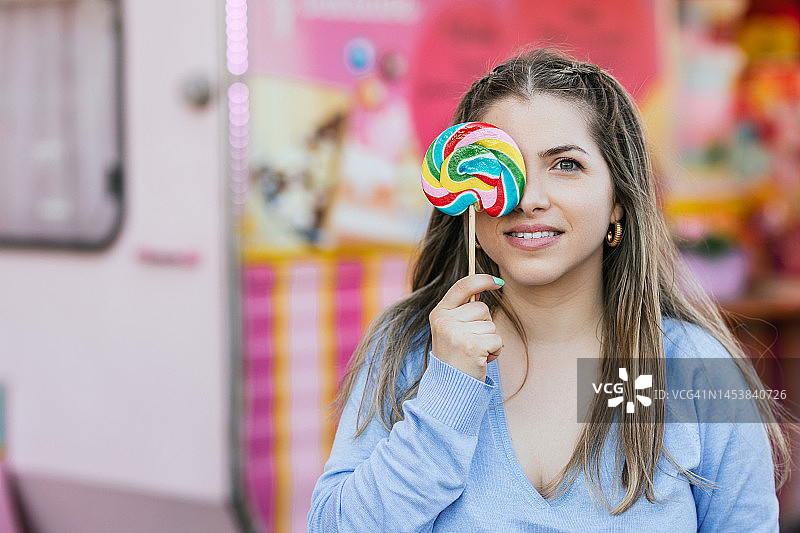 用棒棒糖遮住眼睛的快乐女人图片素材