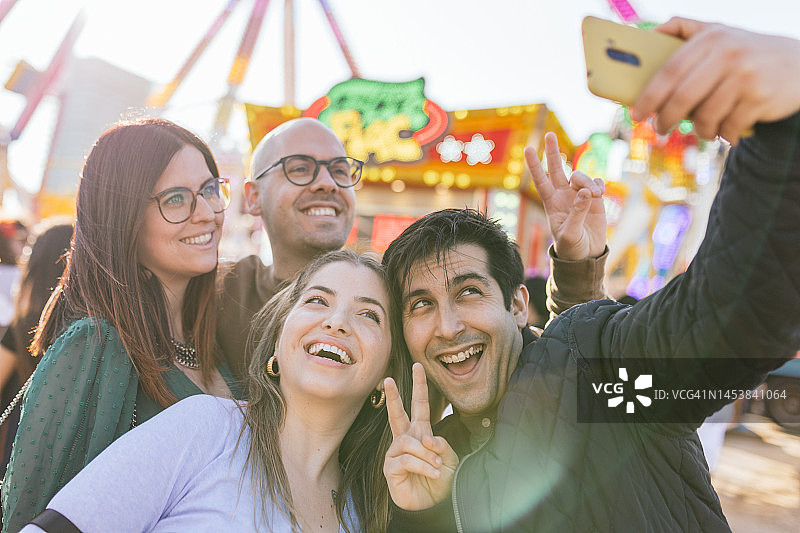 朋友们在游乐园自拍并做出胜利手势图片素材