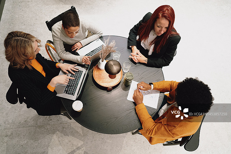 俯视视角：同事们围坐在会议桌旁图片素材