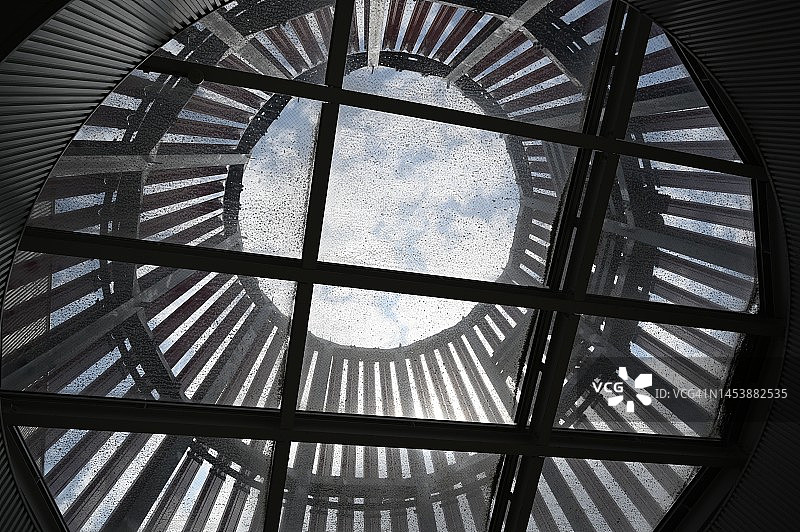 从巨大建筑的中庭仰望天空，玻璃顶棚和格子框架图片素材