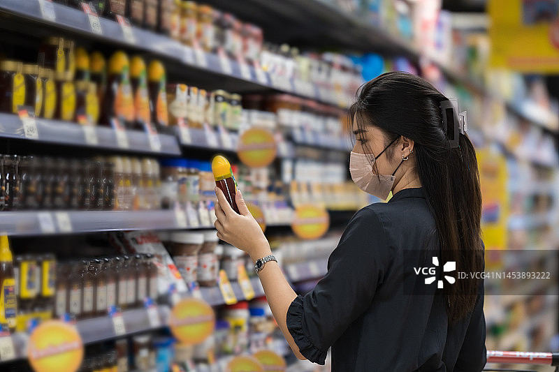 亚裔女子在超市用购物车购买新鲜有机食品图片素材