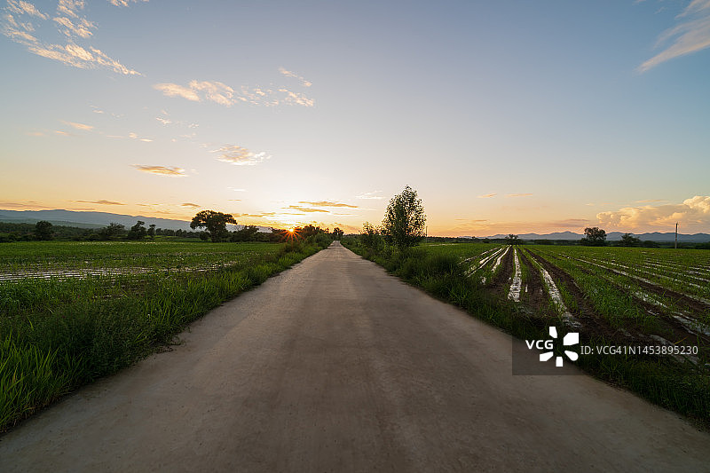 日落时分，田野中的空旷道路图片素材