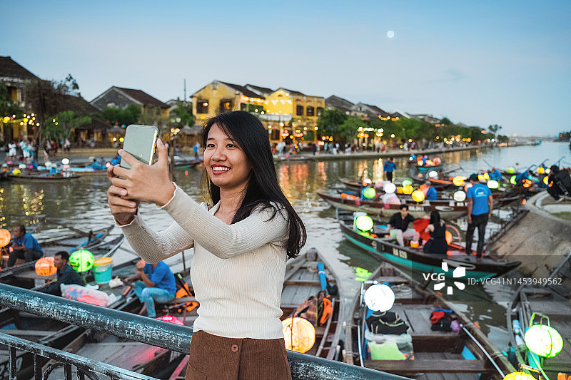 年轻女人在越南会安的桥上看手机图片素材