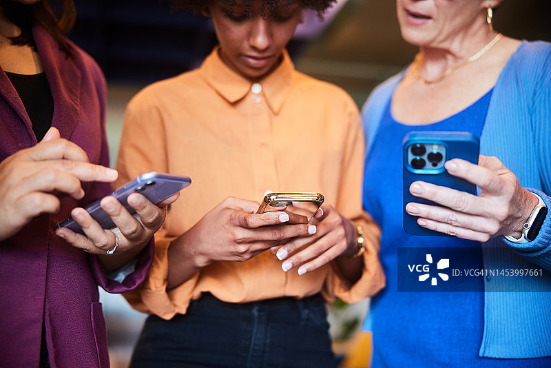 商务女性在办公室休息期间拿着手机站立图片素材