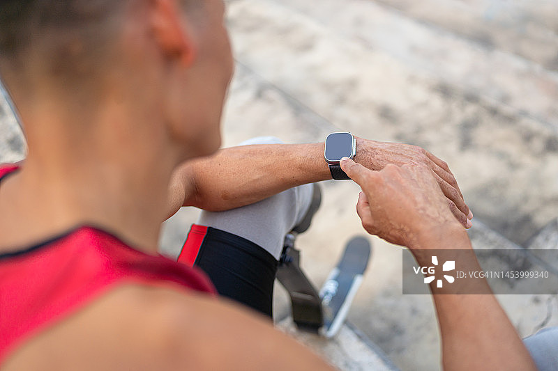 肩后视角：运动员使用智能手表监测跑步训练进度图片素材