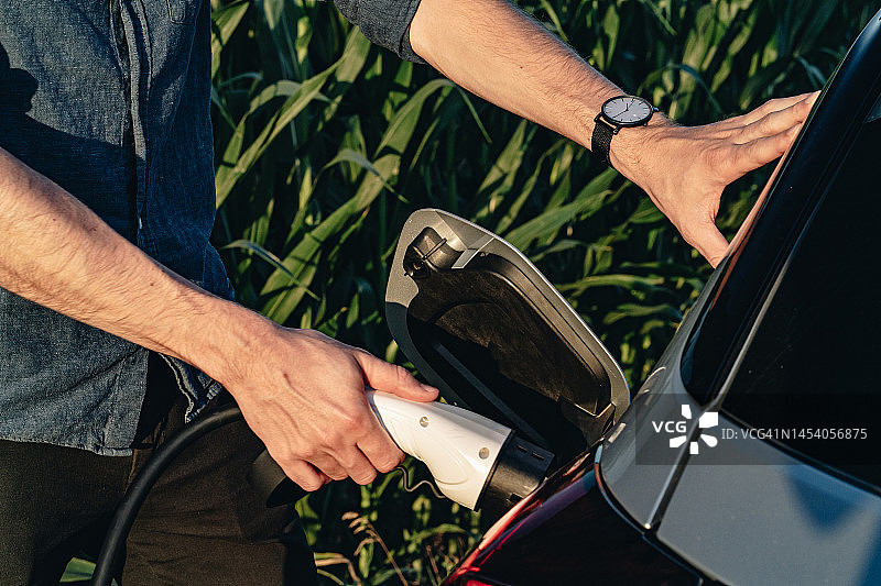 年轻男人为电动汽车充电图片素材