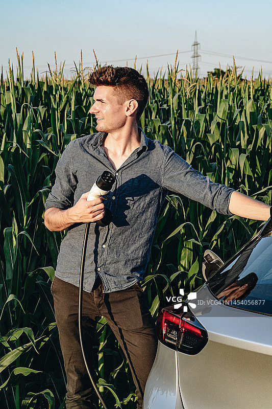 年轻男人为电动汽车充电图片素材