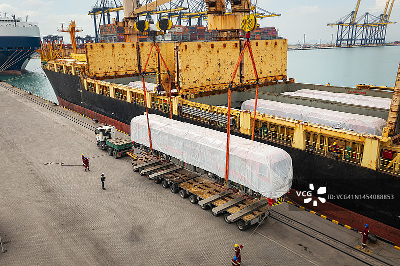 商业港口码头，起重机从集装箱船向卡车卸载火车的鸟瞰图，商业物流进出口运输图片素材